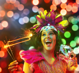 L&auml;chelnde Frau mit einer Wunderkerze und buntem Kost&uuml;m beim Silvester feiern. 