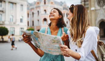 Zwei Frauen schauen auf einen St&auml;dteplan und lachen