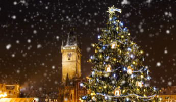 Blick auf den geschm&uuml;ckten Weihnachtsbaum auf dem Weihnachtsmarkt in Prag mit Schneeflocken 